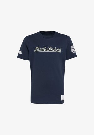 Dunkelblaue Baumwoll-T-Shirt mit dem aufgestickten Schriftzug "Real Madrid" in Weiß, kurzen Ärmeln mit weißem Adidas-Logo auf einer Seite und Vereinswappen am Ärmel.