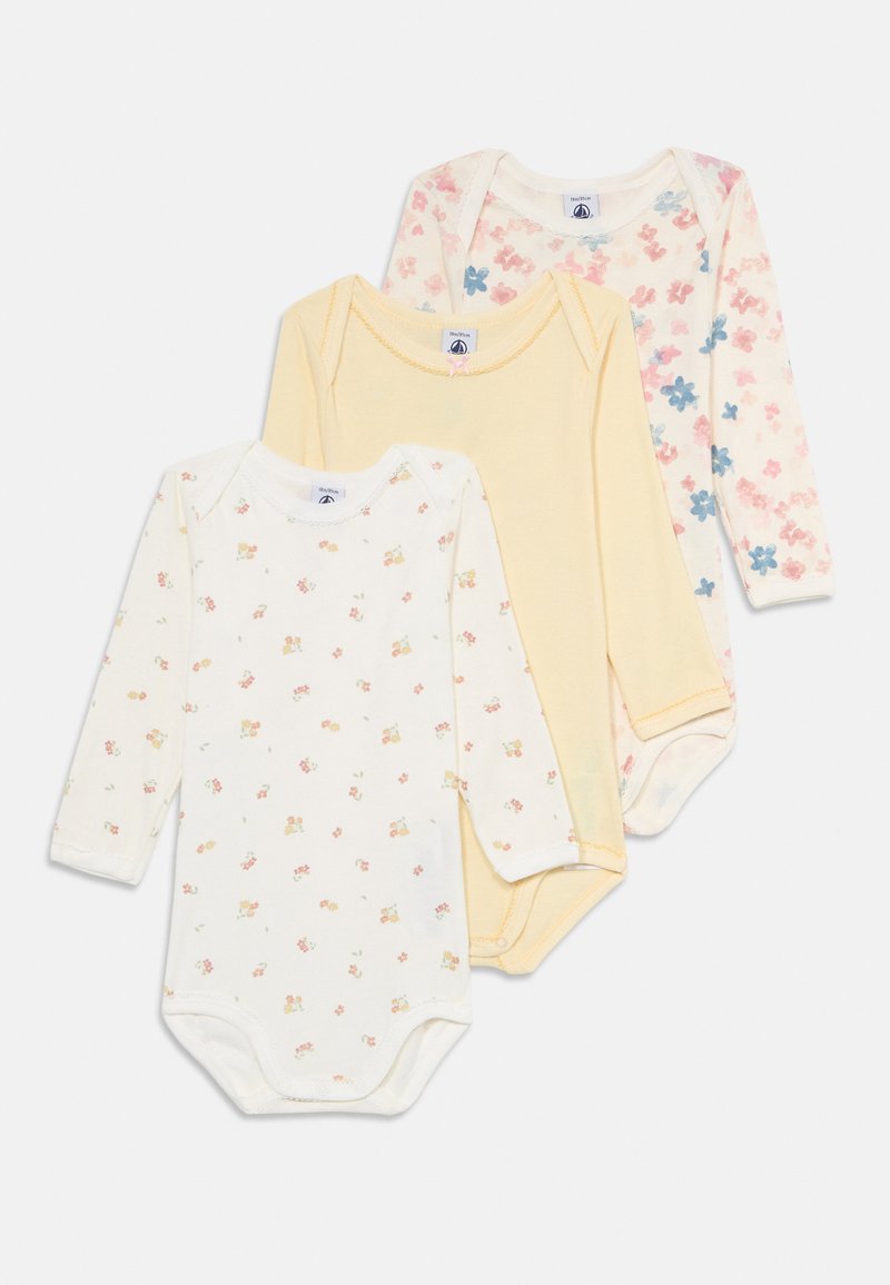 Tre langermede baby-bodyer stablet, en med små oransje blomster, en ensfarget lys gul, og en med rosa og blå blomster.