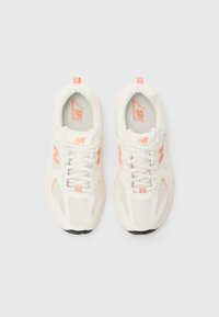 Hvite mesh-sneakers med korallfarger, en polstret såle og polstret krage med logo på tungen. Snøring design.
