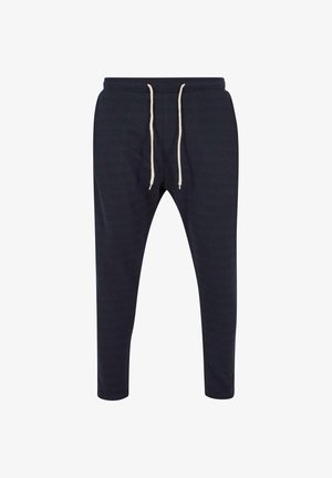 Pantalons de jogging navy en tissu doux, présentant un design fuselé, une taille élastique et un cordon de serrage crème. Surface texturée avec un motif subtil.