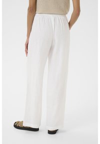 Witte linnen broek met wijde pijpen en een elastische tailleband. Soepele textuur en vloeiende ontwerp, gecombineerd met donkere sandalen.