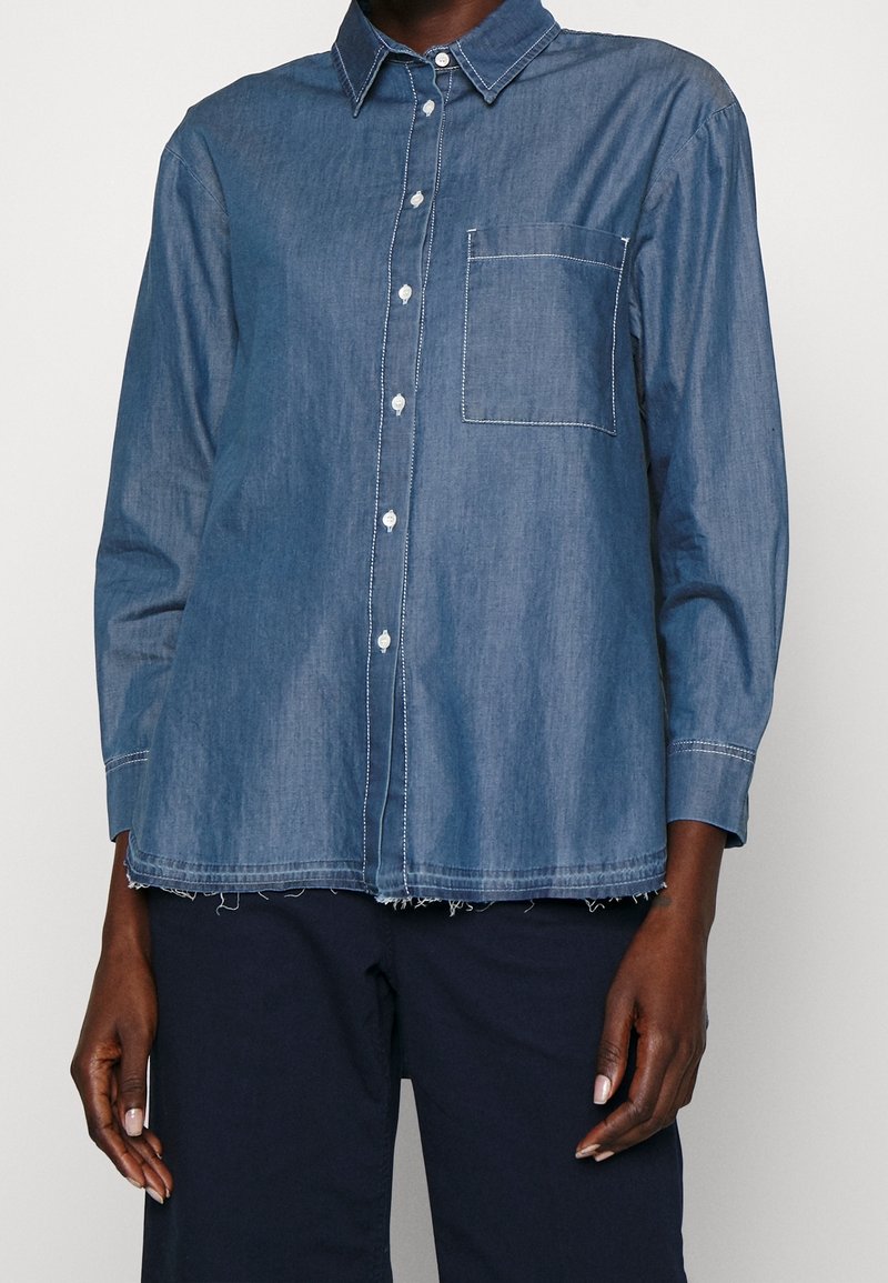 Lichtgewicht, blauw denim overhemd met een button-down kraag, witte stiksels, een enkele borstzak en een rafelige zoomafwerking.