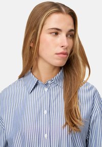 Blue and white striped button-up shirt with a collar, featuring a relaxed fit and smooth texture. Buttons are white and round.