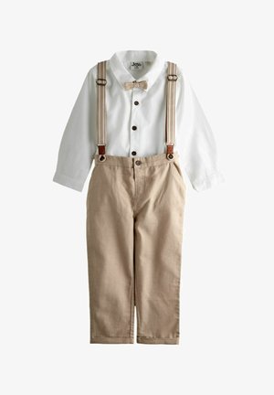 Chemise blanche à manches longues avec boutons, nœud papillon beige, pantalons beiges avec bretelles assorties fixées par des boutons.