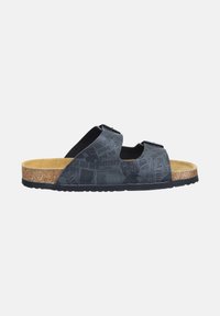 Black slide sandal with cork footbed, two adjustable straps featuring a newspaper print pattern, and a black rubber sole, side view.