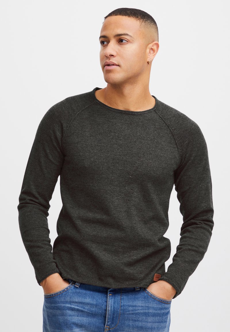 Donkergrijze longsleeve shirt met een ronde hals en raglanmouwen, gemaakt van een gestructureerde stof, gecombineerd met blauwe spijkerbroek.