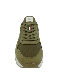 Baskets vert olive en matériau en maille et en suède. Les caractéristiques incluent des lacets ronds, une étiquette logo et une semelle blanche mouchetée.