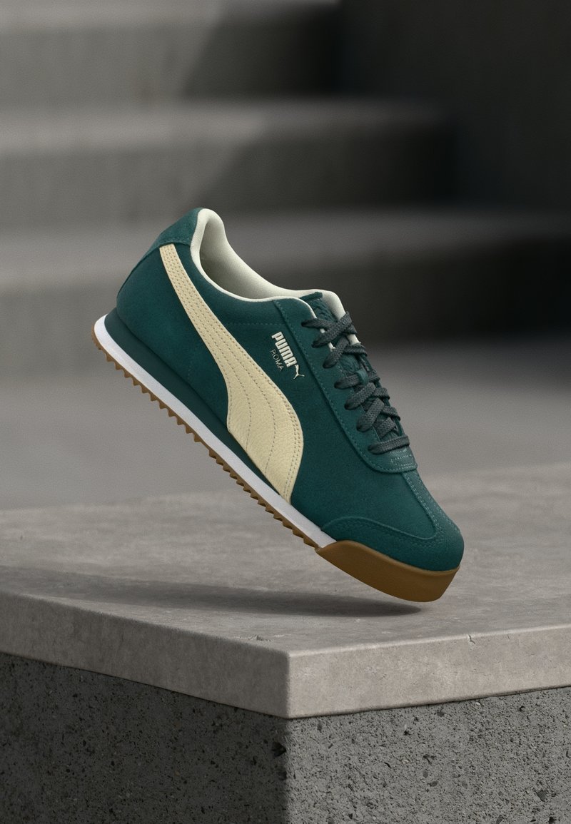 Tenisi verzi din suede cu accente crem, superior texturat, talpă din cauciuc, având un design cu șireturi și un logo de marcă pe lateral.