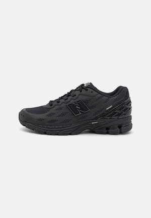 Scarpa da corsa atletica nera con tomaia in mesh, suola spessa ammortizzata e logo marchiato sul lato, fotografata su sfondo bianco.