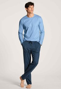 Lichtblauw langemouwen shirt in combinatie met donkerblauwe pyjamabroek met witte en blauwe verticale strepen en kleine stippen. Casual fit.