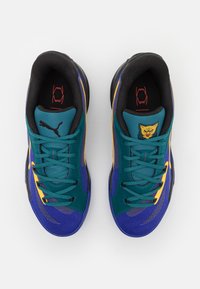 Puma sneakers in teal, paars en geel; mesh en synthetische materialen, platte veters, gevoerde kraag en een kattenlogo op de tong.