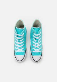 Sneaker alte in cotone turchese brillante con lacci bianchi, suola in gomma nera a contrasto e punta bianca.