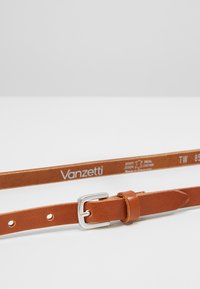 Ceinture en cuir brun avec une boucle en métal argenté, dotée de trous de réglage et d'un logo embossé sur la sangle.