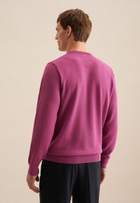 Maglione aderente rosa a maglia con polsini e orlo a coste, che mette in mostra un tessuto texturizzato e un design classico a girocollo. Vista posteriore esibita.