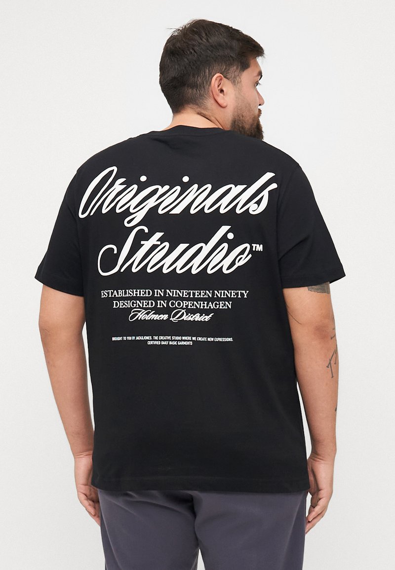 Schwarzes Baumwoll-T-Shirt mit weißem Text auf der Rückseite, stilvolle Schrift für "Originals Studio" und zusätzlichen gedruckten Details darunter.