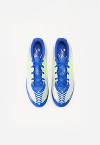 Des chaussures de football en bleu et jaune, avec un design léger, une tige en matériau synthétique et une semelle à motifs pour une meilleure traction. Lacets en bleu.