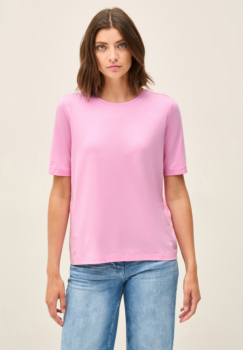 Maglietta rosa a maniche corte con scollatura rotonda, realizzata in tessuto morbido. Abbinata a jeans in denim azzurro chiaro, con una vestibilità rilassata.