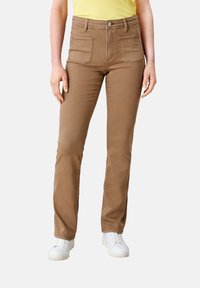 Brązowe spodnie straight-leg z dwoma przednimi kieszeniami, wykonane z miękkiego materiału. Połączone z białymi trampkami i żółtą bluzką z prążków.