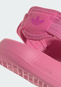 Rosa Sport-Sandalen mit weichen, strukturierten Oberriemen, flacher Gummi-Sohle und geprägt Branding-Details. Verstellbarer Klettverschluss.