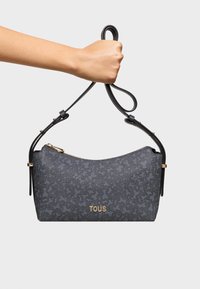 Borsa a spalla grigia con un motivo texturizzato, dettagli in pelle nera e hardware dorato. Presenta una chiusura con zip e una tracolla regolabile.