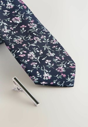 Marineblauer Krawatte mit floralem Muster in Pink- und Grüntönen, begleitet von einer silbernen Krawattennadel mit einem dunkelgrünen Akzent.