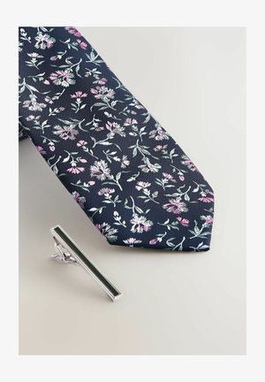 Cravate navy avec motif floral dans des tons de rose et de vert, accompagnée d'une pince à cravate en argent avec un accent vert foncé.