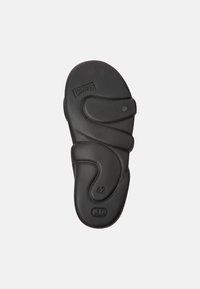 Black rubber shoe sole with contoured design. Features stamped brand name "Camper" and size "42." Smooth texture with curved lines.
