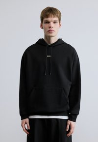 Μαύρο φούτερ με κουκούλα από μαλακό υλικό, με τσέπη μπροστά και μικρό λευκό λογότυπο "BOSS" στο στήθος. Μακριά μανίκια; άνετη γραμμή.