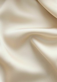 Tissu satin crème lisse avec de doux plis et une légère brillance reflétant la lumière.