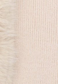 Tessuto in maglia di lana color rosa pallido, che sfuma in un morbido bordo di pelliccia sintetica. La superficie testurizzata presenta costine verticali su tutta la lunghezza.