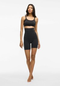 Top sportivo nero e pantaloni corti a vita alta realizzati in tessuto liscio e elastico. Il design presenta cuciture minime e una silhouette aderente.