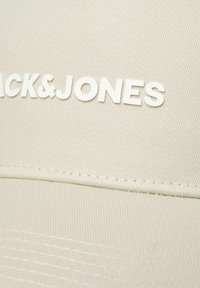 Khaki czapka o fakturowanym wykończeniu, z białym logo "BLACK&JONES" z przodu oraz kontrastującymi detalami przeszycia wzdłuż szwów.