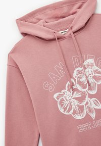 Roze hoodie van katoen met een witte bloemmotief en de tekst "SAN DIEGO EST. 1994." Gladde textuur en verstelbare koordjes.