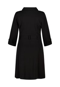 Zwarte jurk met een kraag, driekwart mouwen, een riem op de taille en een uitlopende rok. Gladde stof met een effen kleur.