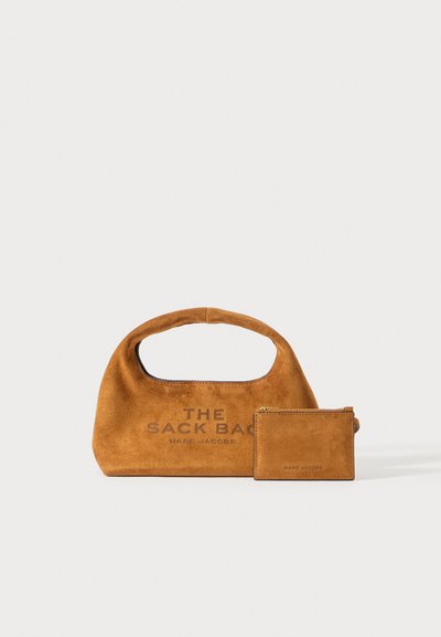 Brown suede handbag labeled "The Sack Bag" with matching brown suede zip pouch beside it on a white background.