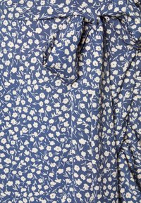 Floral print fabric in blue with white flowers, featuring a tied knot detail. Soft texture, intricate pattern, suitable for clothing.