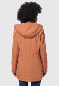 Giacca arancione da donna con cappuccio, realizzata in tessuto morbido, con vita regolabile tramite coulisse e taglio di lunghezza media.