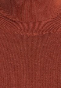 Maglione a collo alto lavorato a maglia di un profondo color arancio, caratterizzato da una texture a coste e una finitura liscia intorno al collo e al corpo.