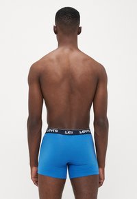 Boxeri scurți albaștri cu un tiv negru Levi's, textură netedă, design ajustat și croială de înălțime medie, văzuți din spate.