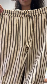 Bēša un brūna svītraina bikses ar elastīgu jostu un auklu. Viegls audums ar gludu faktūru. Redzamas priekšējās krokspletes.