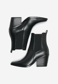 Bottines en cuir noir avec un talon épais, des panneaux latéraux élastiques, une pointe effilée et un accent texturé sur le talon. Fini lisse et design épuré.