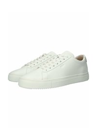 Baskets blanches en cuir avec un profil bas, un bout rond et une semelle en caoutchouc plate. Elles présentent un design à lacets et un marquage minimal sur le côté.