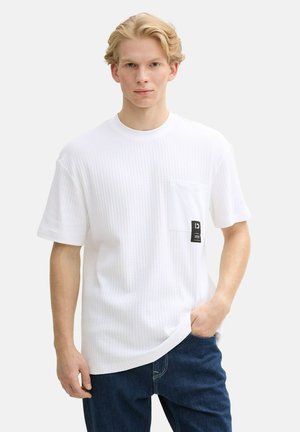 Witte T-shirt met korte mouwen en een textured patroon, met een borstzak en een zwart labelaccent. G gedragen met donkerblauwe denim broeken.