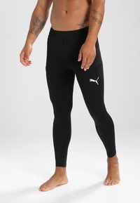 Fekete sportos leggings rugalmas anyagból, fitted szabással, magas derékkal és fehér logóval a combon.