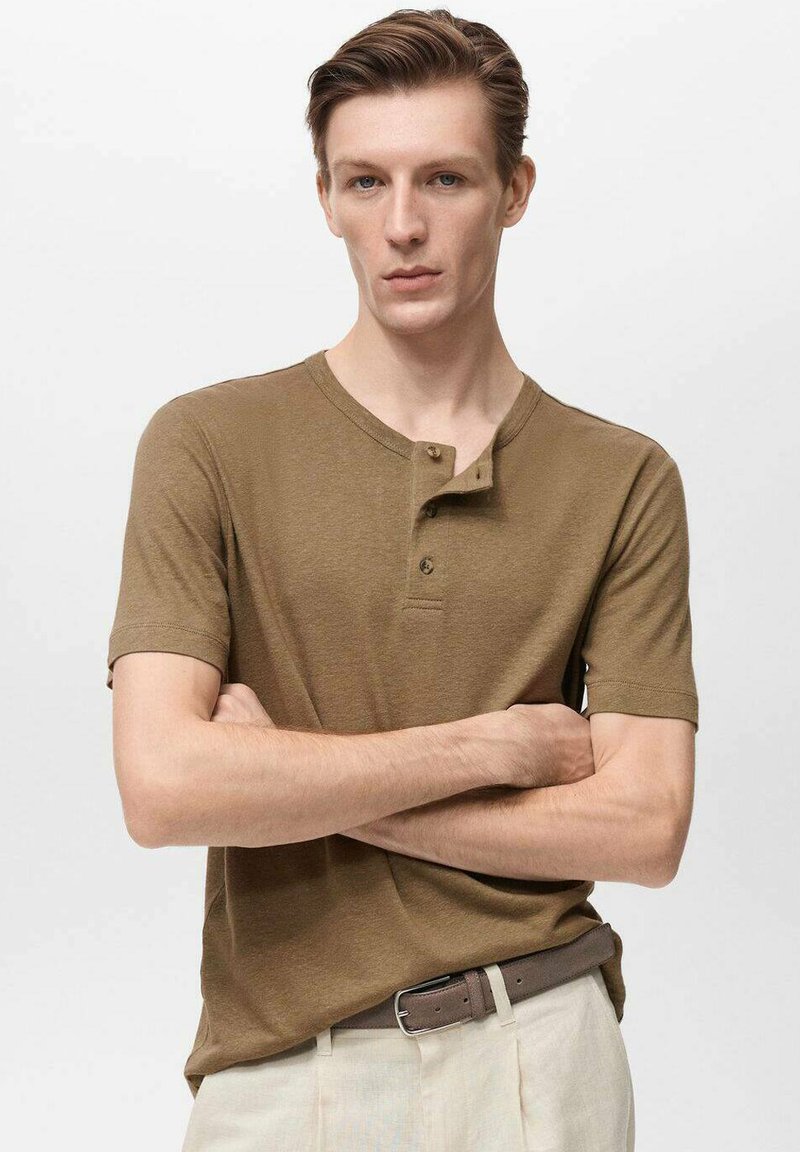 Rjava kratka majica henley z mehkega materiala, ki ima okroglo vratno izreza, gumbasti zapenjanje in teksturno podrobnost.