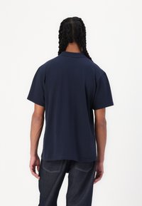 Navy short-sleeve polo shirt with a flat collar, lightweight fabric, straight cut, and visible stitching details on the hem.