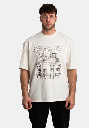 Camiseta de algodón blanca con un dibujo en línea negro de una escena de bar y el texto "PEGADOR Aroma de verano" impreso en el frente.