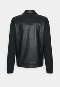 Giacca nera con retro in pelle e maniche in tessuto nero uniforme. Presenta un colletto e polsini a coste all'orlo e alle maniche.