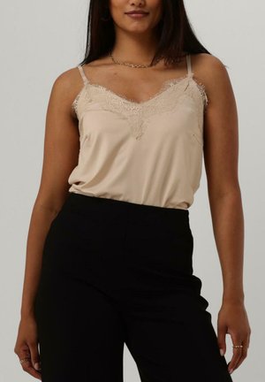 Satin beige camisole with lace trim, featuring thin shoulder straps and a relaxed fit, paired with high-waisted black trousers.