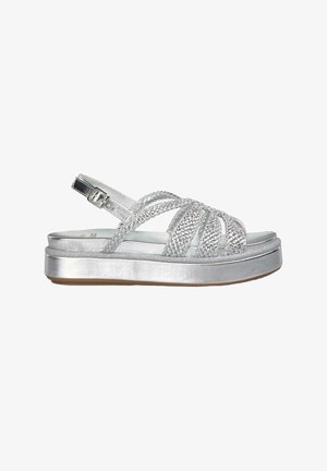 Sandale plateforme argentée avec des brides tressées et une fermeture à boucle. Fabriquée en matériau métallique avec une texture lisse. Semelle plate et antidérapante.